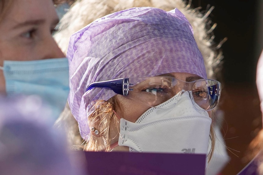 Nurse wearing hair net, mask and safety glasses.