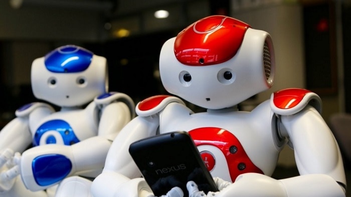 One red and one blue robot holding a smart phone.