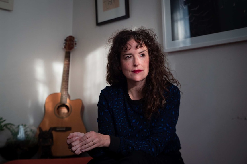 Author Jess Hill looking out a window in her home