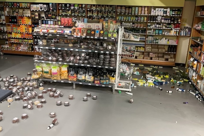 shelves of food with the products smashed on the ground.