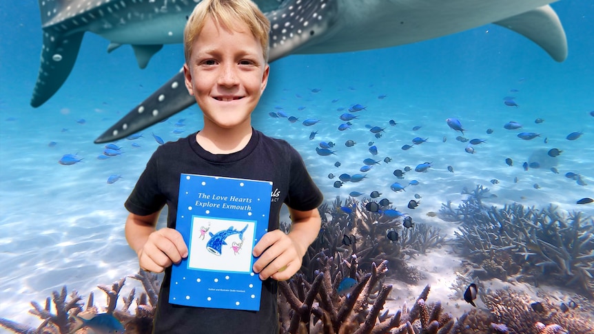 A young boy holds a copy of his book. In the background a tropical underwater scene with a whale shark swimming above.