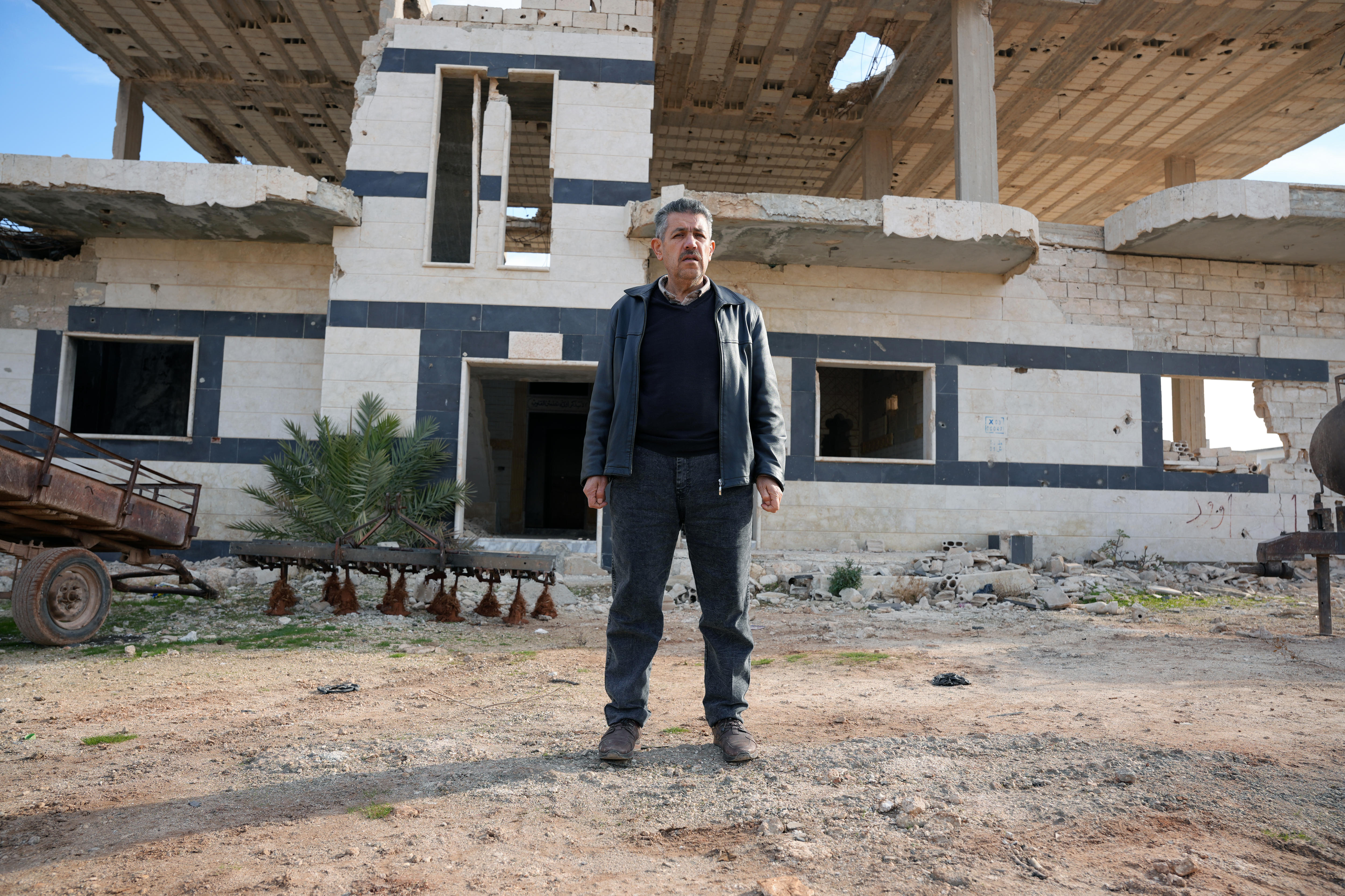 Um homem está em frente a um prédio em ruínas.