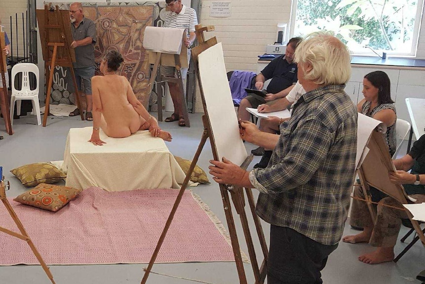 Life drawing class watching Nude Model Jo Ernst sitting in the middle of the room.