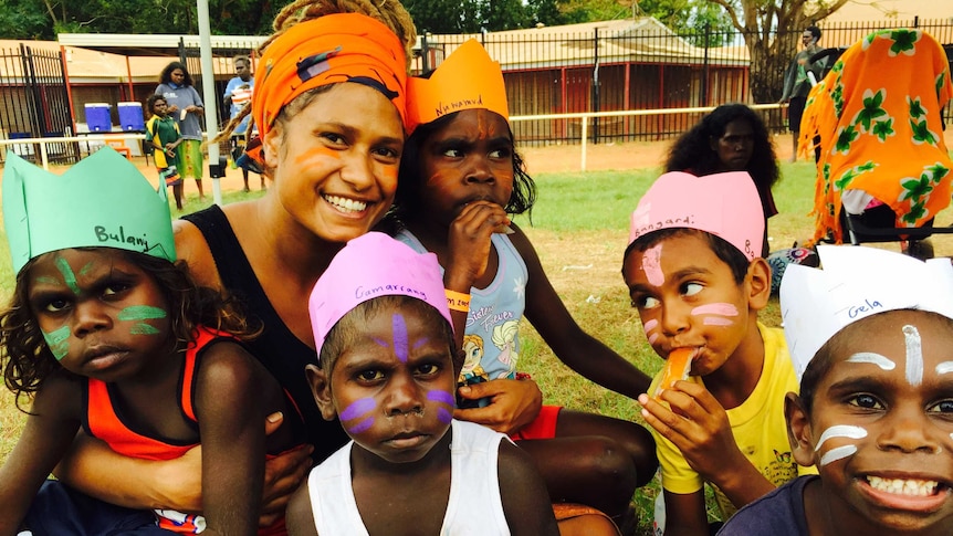 Alice Eather sits embracing two children on her lap and three others nearby wearing paper crowns.