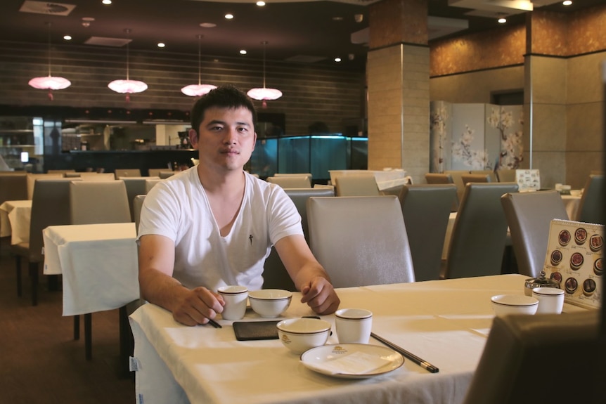 Emperor's Kitchen director Yidi Pan sits at a table in an empty restaurant.