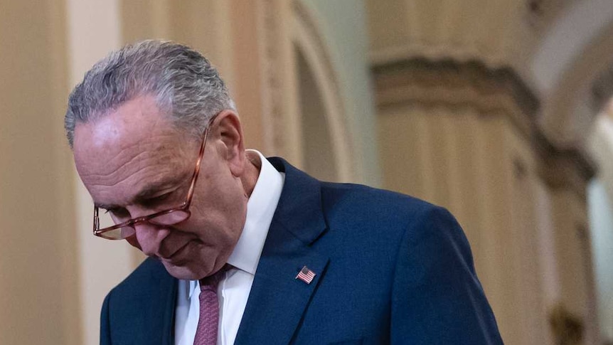 Senate Minority Leader Chuck Schumer walks out with his head down