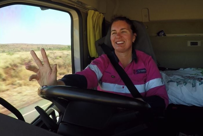 A female driver signals the 'trucky wave' to an oncoming driver from her seat.