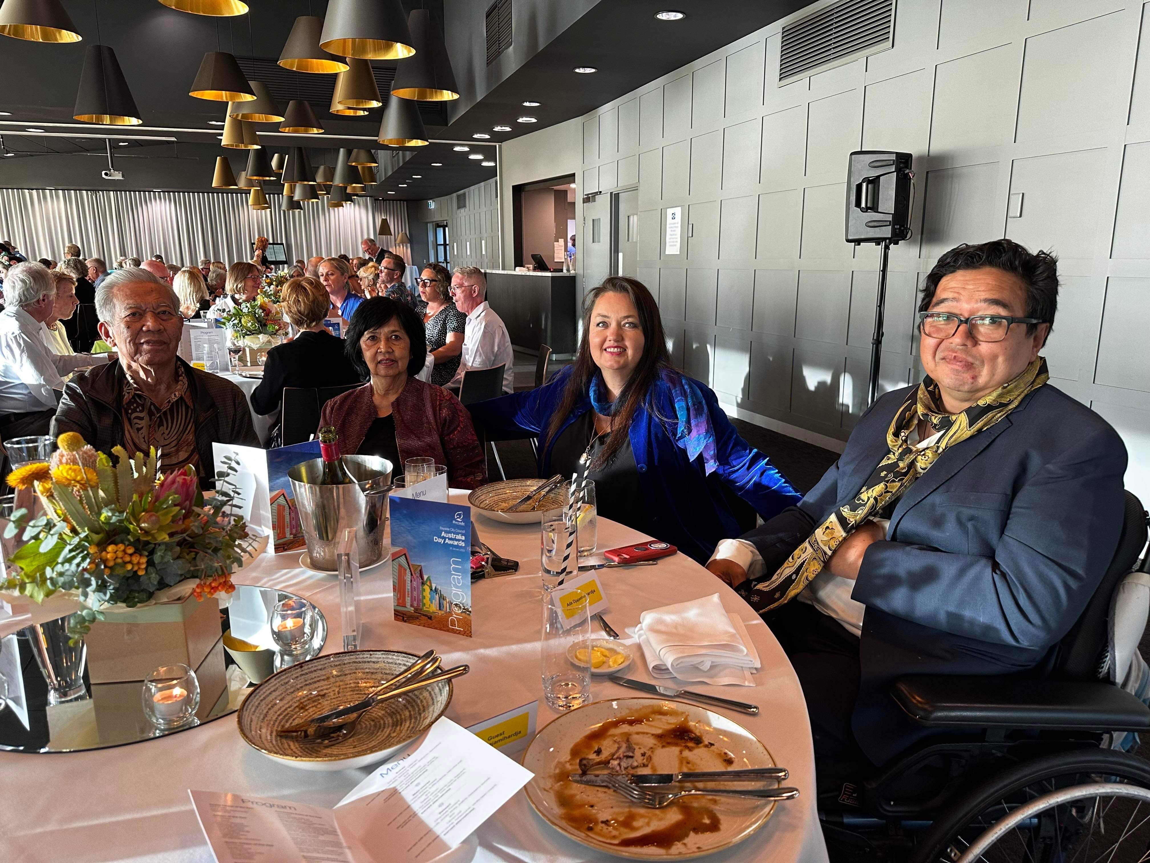 Four people sit at a table in a restaurant while looking at the camera