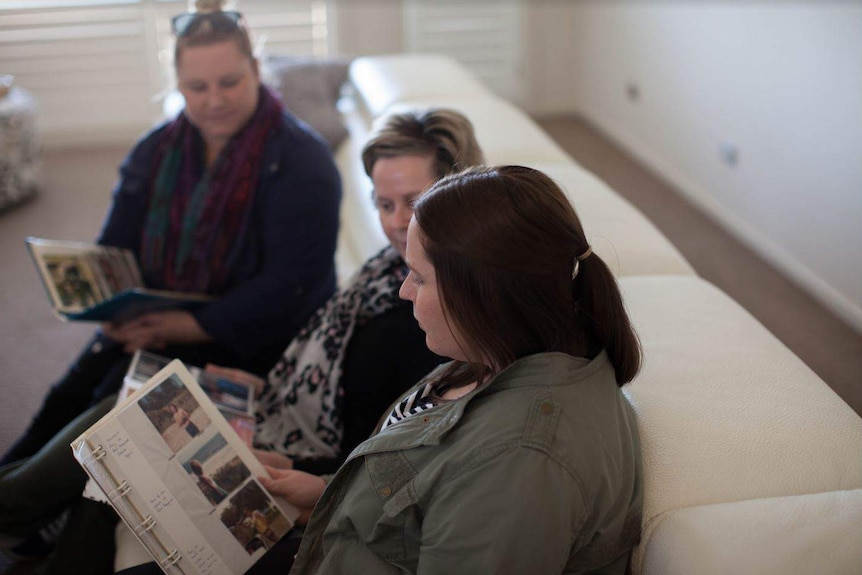 Sharon Jenkins and her daughters sitting together, looking at old family photos