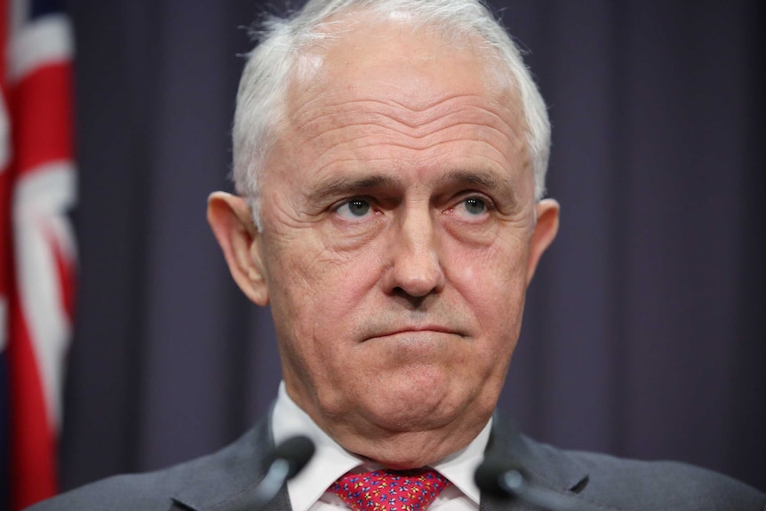 Malcolm Turnbull, with a furrowed brow and down-turned mouth, looks towards the journalists at a press conference.