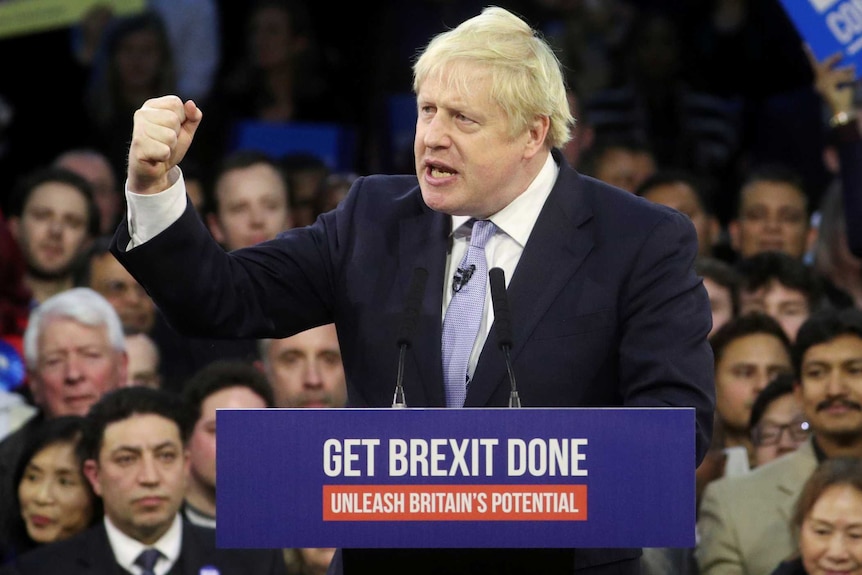 Boris Johnson stands with his fist raised behind a lectern that has the slogan 'get Brexit done' written on it.
