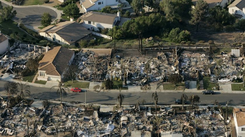 A lone house stands surrounded by burnt out homes