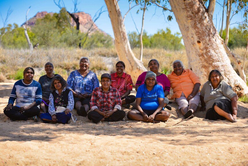 Tangentyere Women's Family Safety Group members sit under a tree