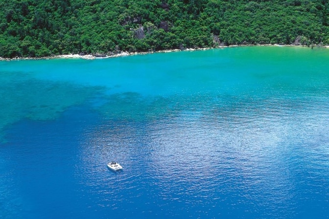 Aerial of Cid Harbour with the shoreline and a boat in the water.