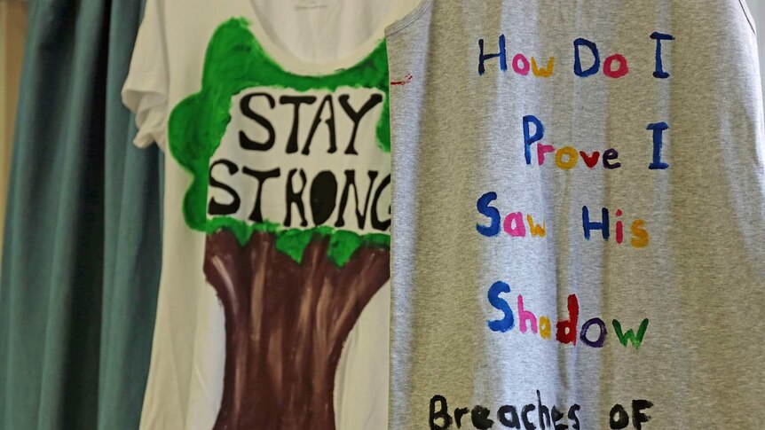 'How do I prove I saw his shadow?' and 'Stay strong' painted on T-shirts by domestic violence survivors
