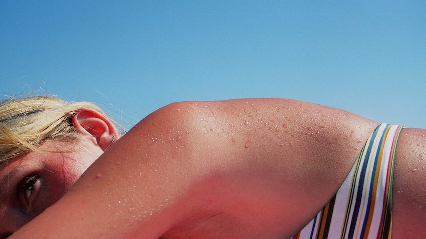 A woman sunbaking in the sun on a beach.