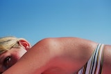 A woman sunbaking in the sun on a beach.