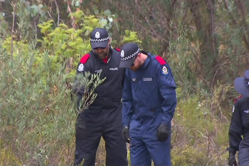 Three police officers walking through bushland