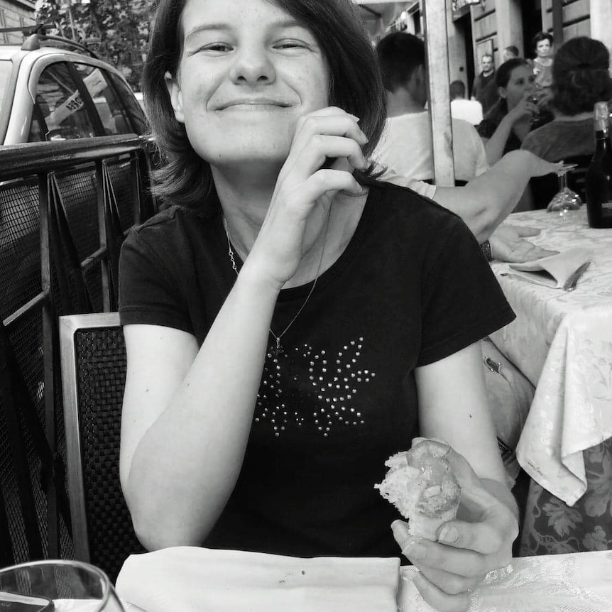 A young woman sits at a cafe, eating.