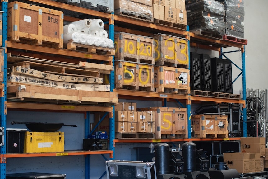 Wooden boxes on shelves with yellow numbers spray painted on them.