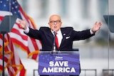 Rudy Giuliani gestures his arms outward as he speaks at a Trump supporters rally.