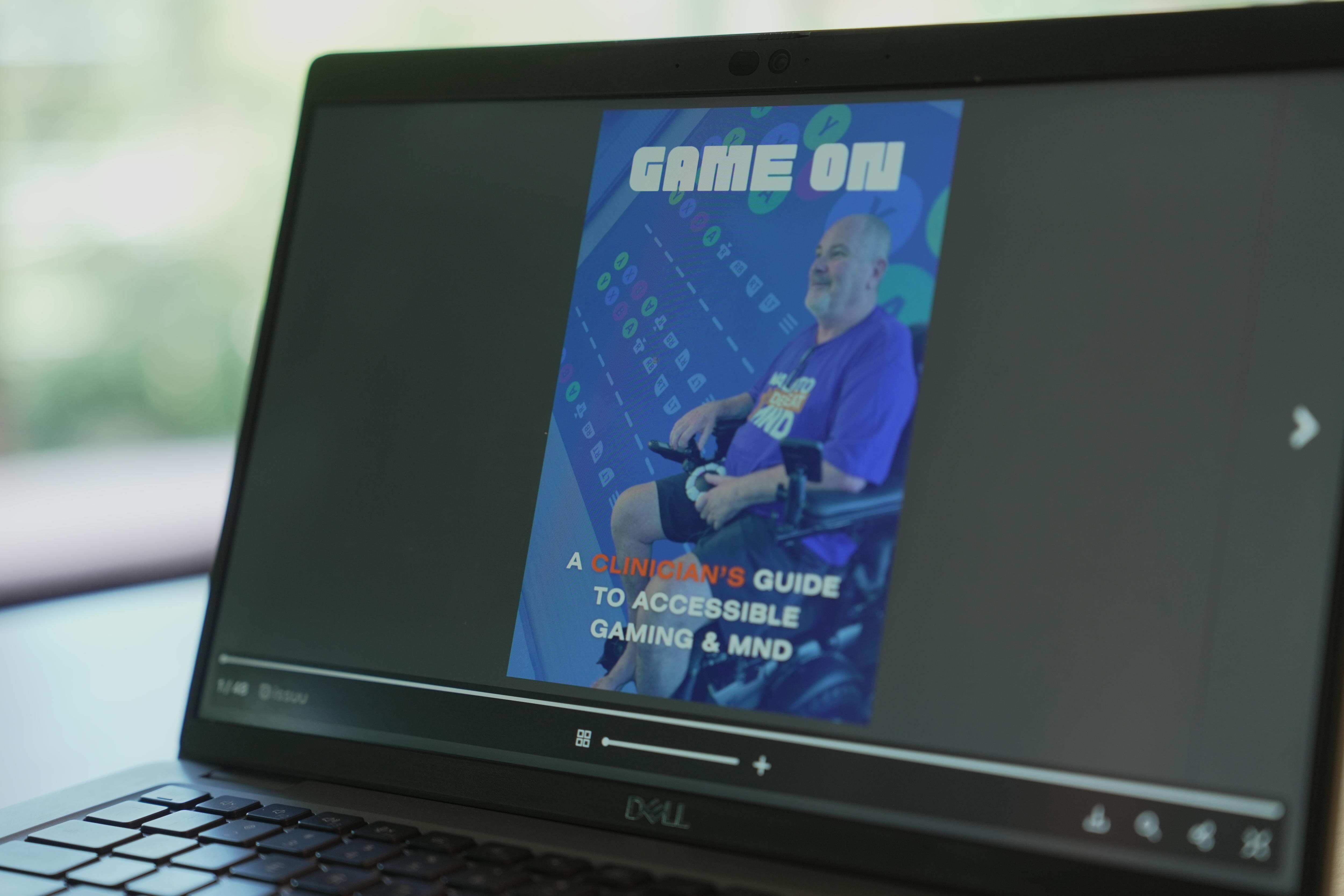 A photo of a laptop with a graphic on the screen reading "Game on: a clinician's guide to accessible gaming and MND".