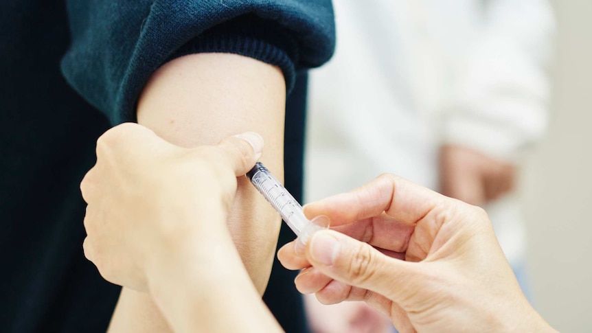 Female doctor giving a vaccination shot to a young woman.