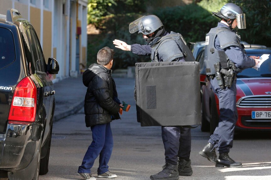 A French police officer speaks to a child outside a school in Marseille