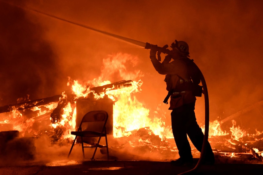 A firefighter sprays water into the flames.