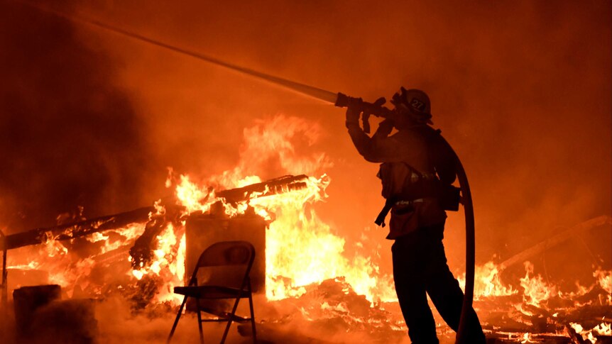 A firefighter sprays water into the flames.