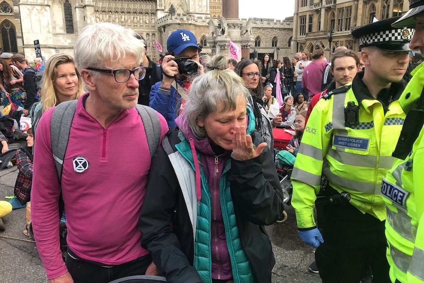 Climate change protester in the streets of London, police officers next to them.