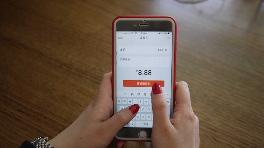 A woman holds a mobile phone that shows messaging app WeChat.