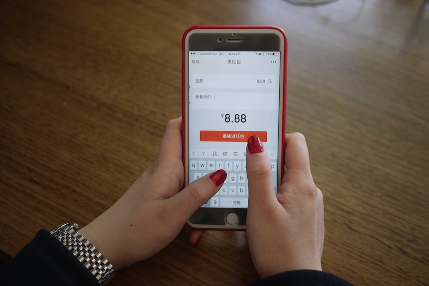 A woman holds a mobile phone that shows messaging app WeChat.