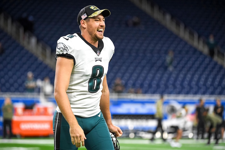 An Australian NFL player laughs while wearing his Philadelphia Eagles uniform.