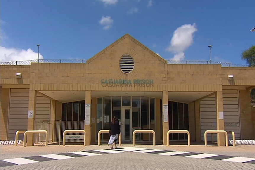 A wide shot of the front entrance to Casuarina Prison under a blue sky.