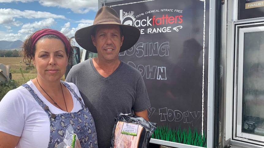 The owners of Backfatters Free Range Pig Farm stand in front of their cold truck of pork products at their property.