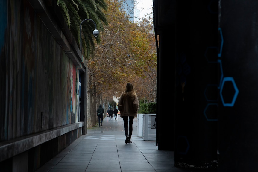 A woman walks down empty Melbourne street with her back to the camera.