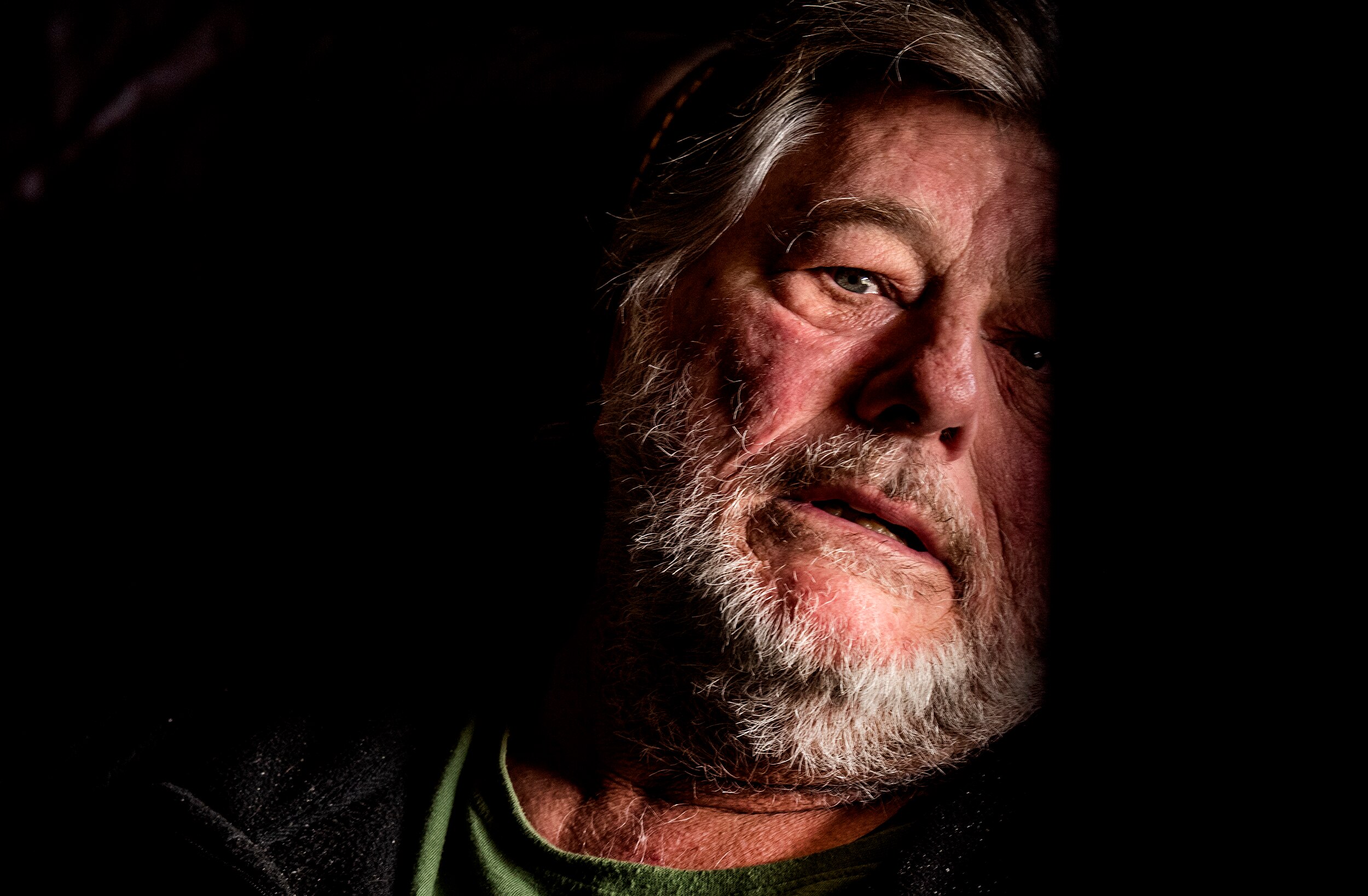 A bearded man in a darkened room.