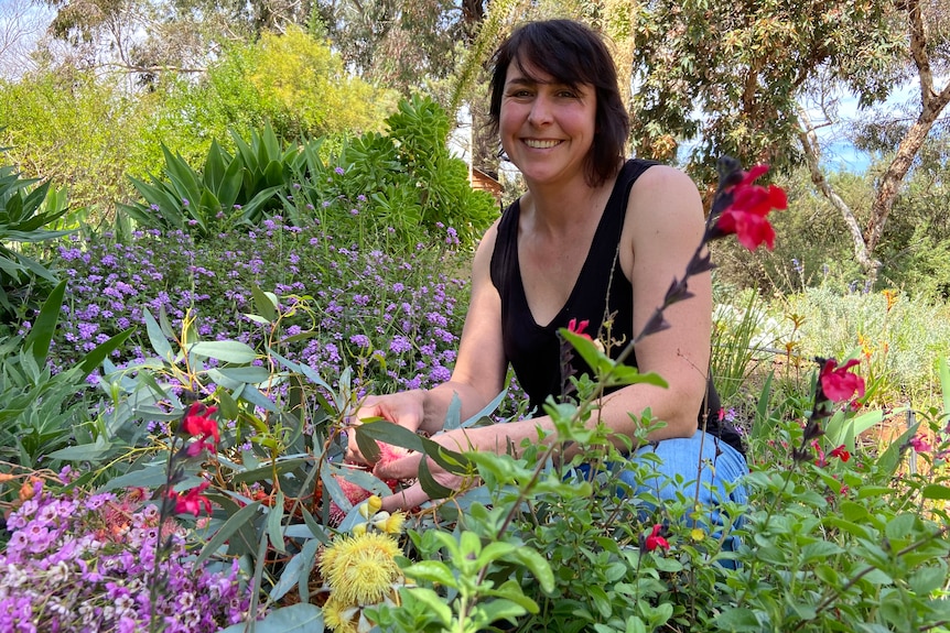 Woman in black top smiling in a colourful cottage garden