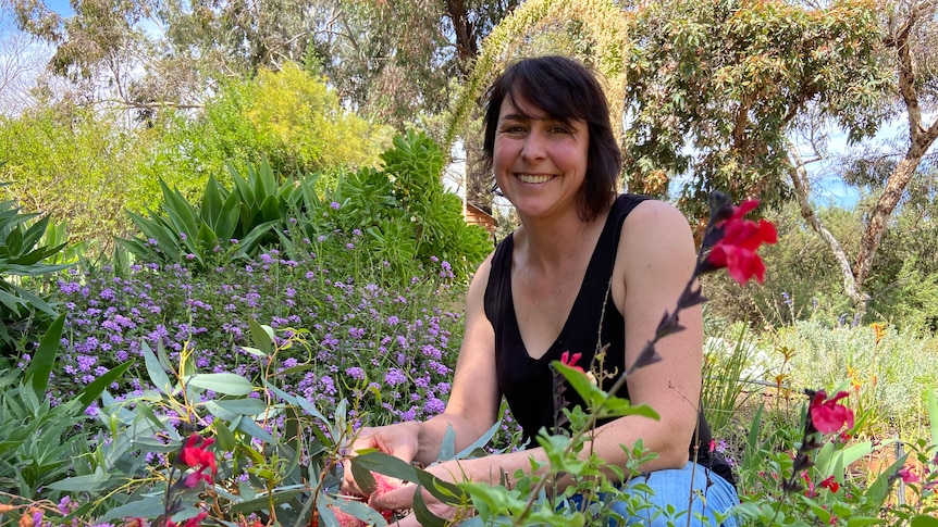 Woman in black top smiling in a colourful cottage garden