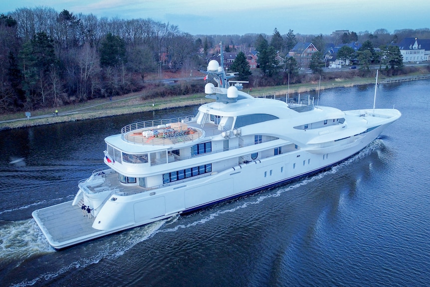 A three-storey super yacht sailing down a river in canal 