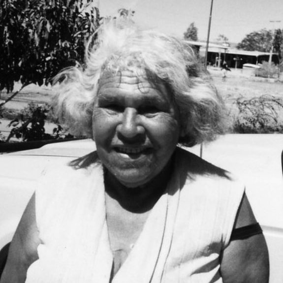 The black and white photo shows an elderly Queenie smiling, with white hair.