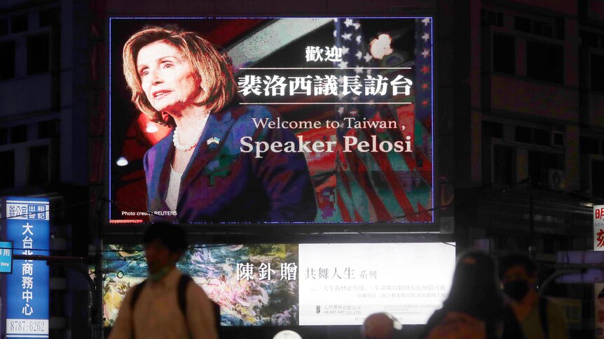 周二，在台湾台北，人们走过欢迎美国众议院议长佩洛西的广告牌。