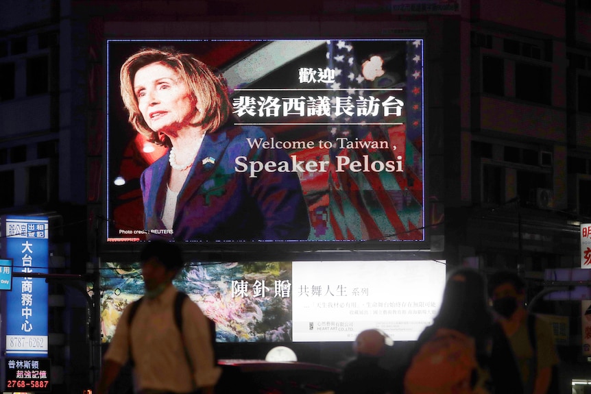 People walk past a billboard welcoming U.S. House Speaker Nancy Pelosi, in Taipei, Taiwan, Tuesday,