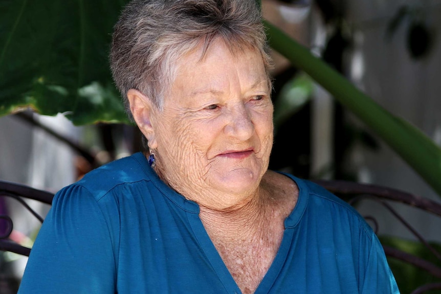 An older woman in a blue top in her garden.