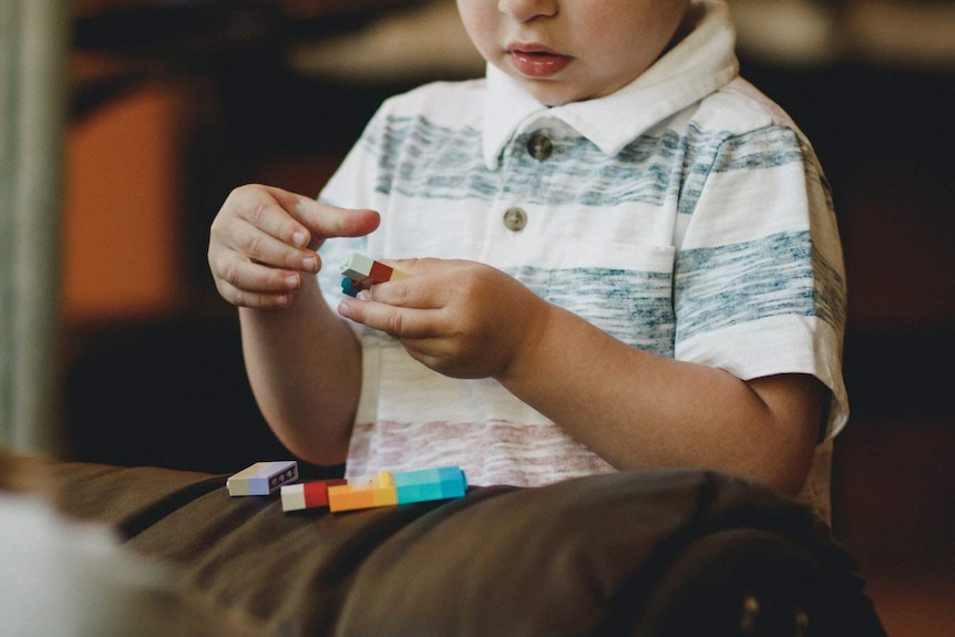 A child plays with blocks on a sofa.