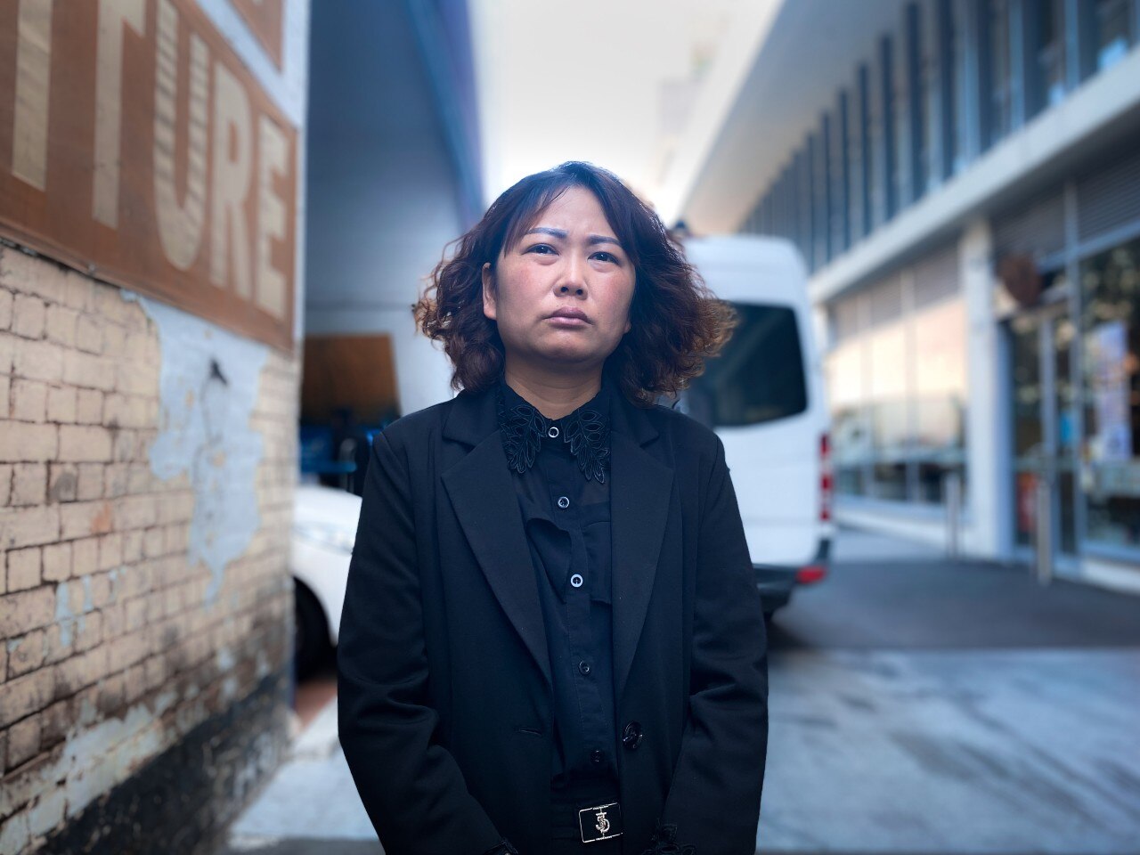 A woman wearing all black stands in a lane.