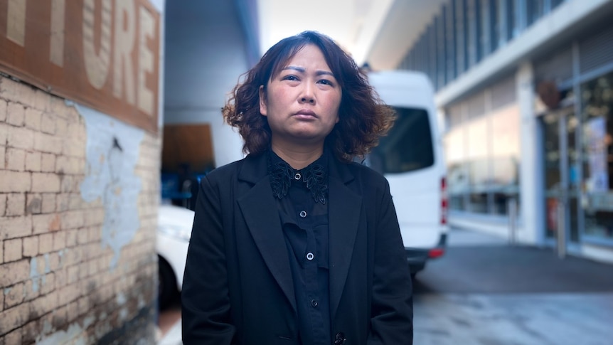 A woman wearing all black stands in a lane.