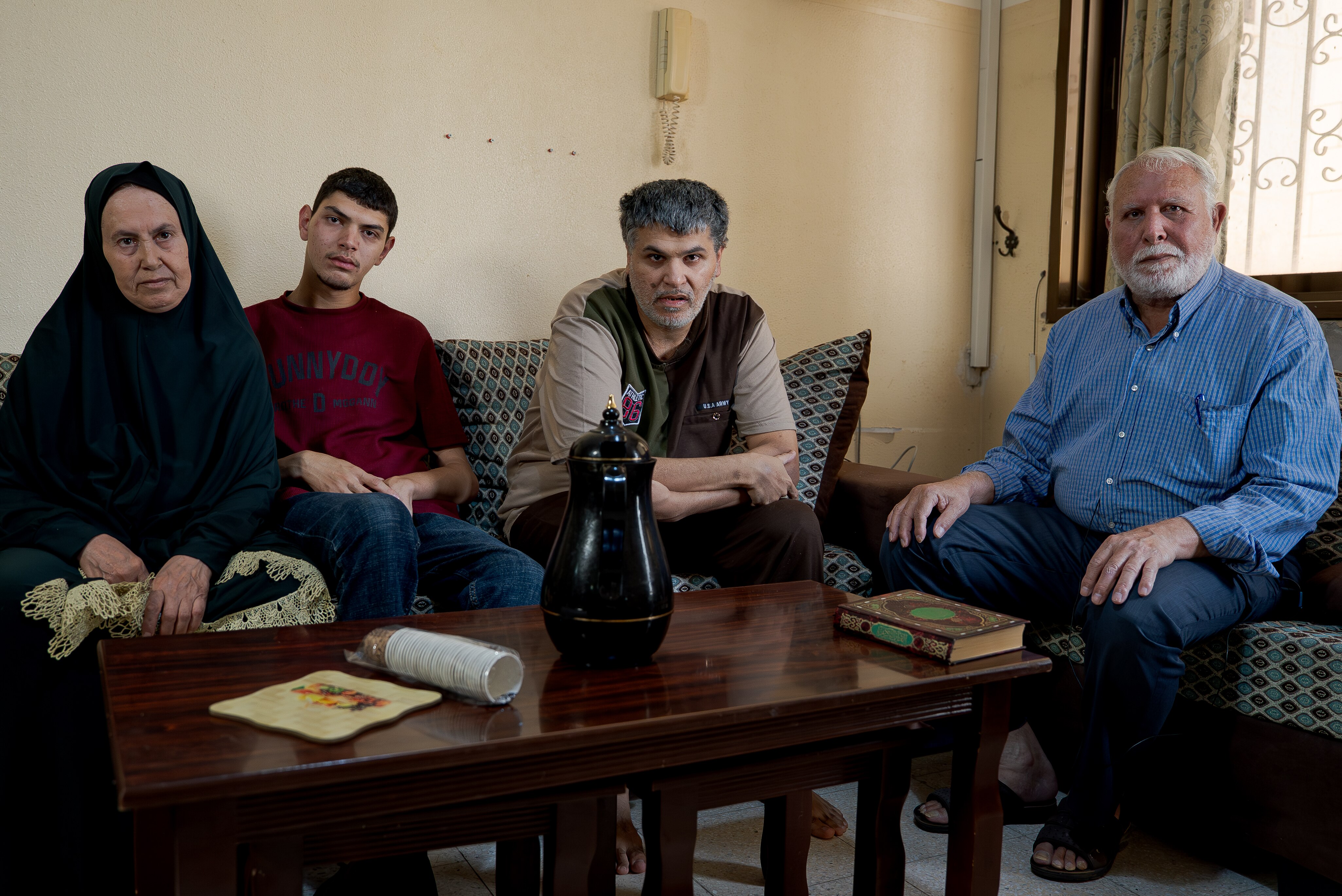 Youssef Alayan (right), his wife (left) and two sons sit in their living room.