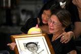 Two women cry as they hold a photograph of journalist Percival Mabasa.